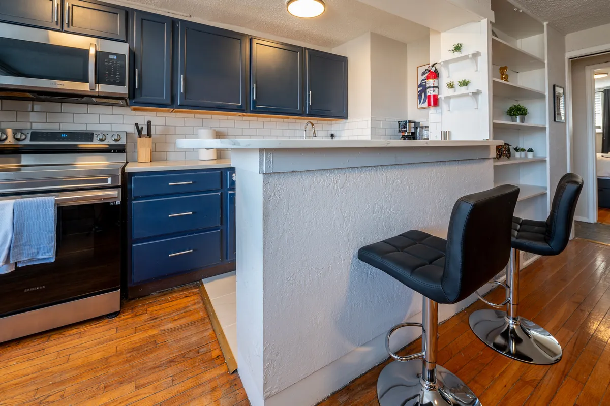 A spacious kitchen island with bar stools, stainless steel appliances, and a bright, open atmosphere. The space is set up for cooking, socializing, and enjoying meals, capturing the multi-functional nature of the kitchen and dining nook.